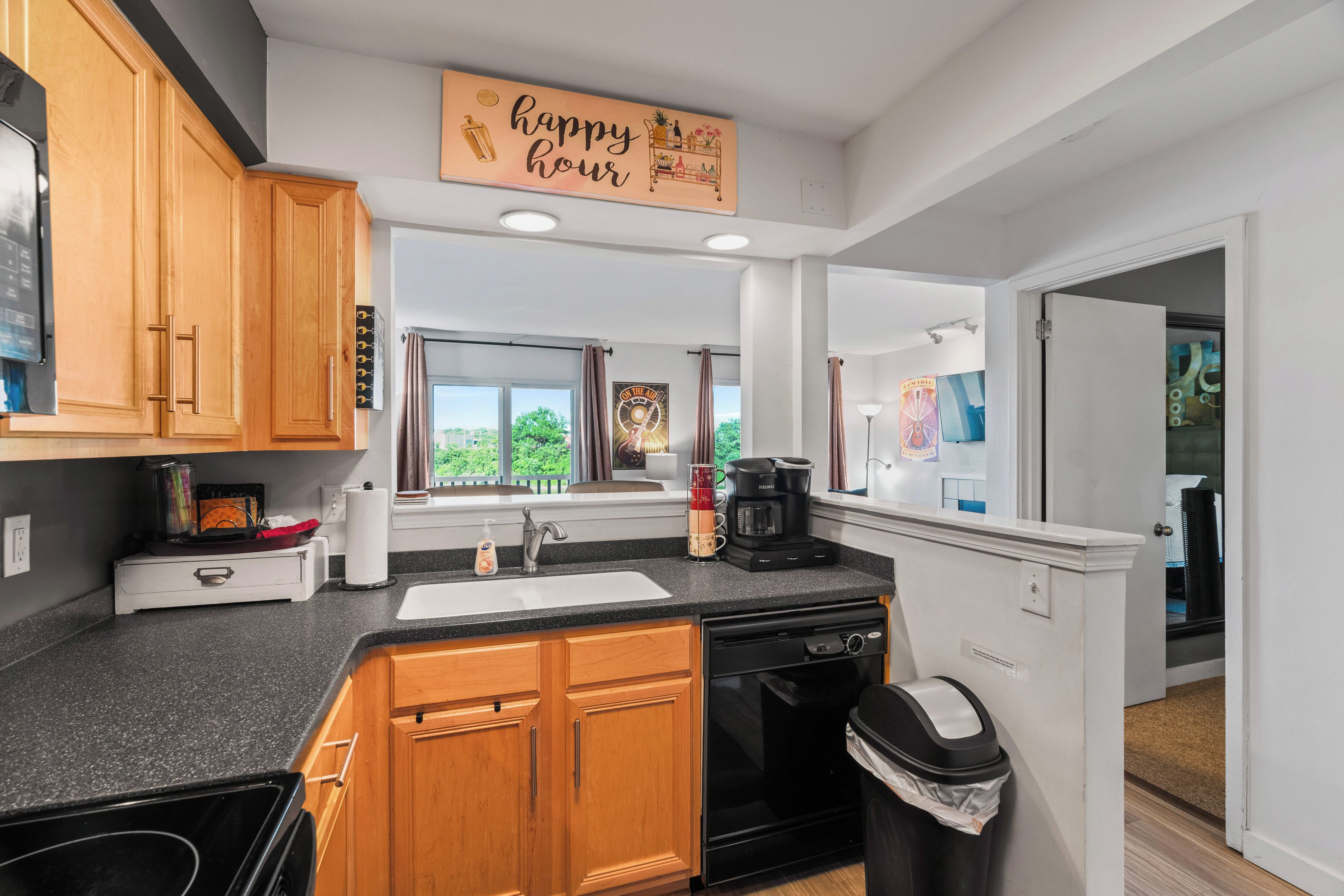 A modern kitchen with wooden cabinets, a black dishwasher, and a coffee maker.