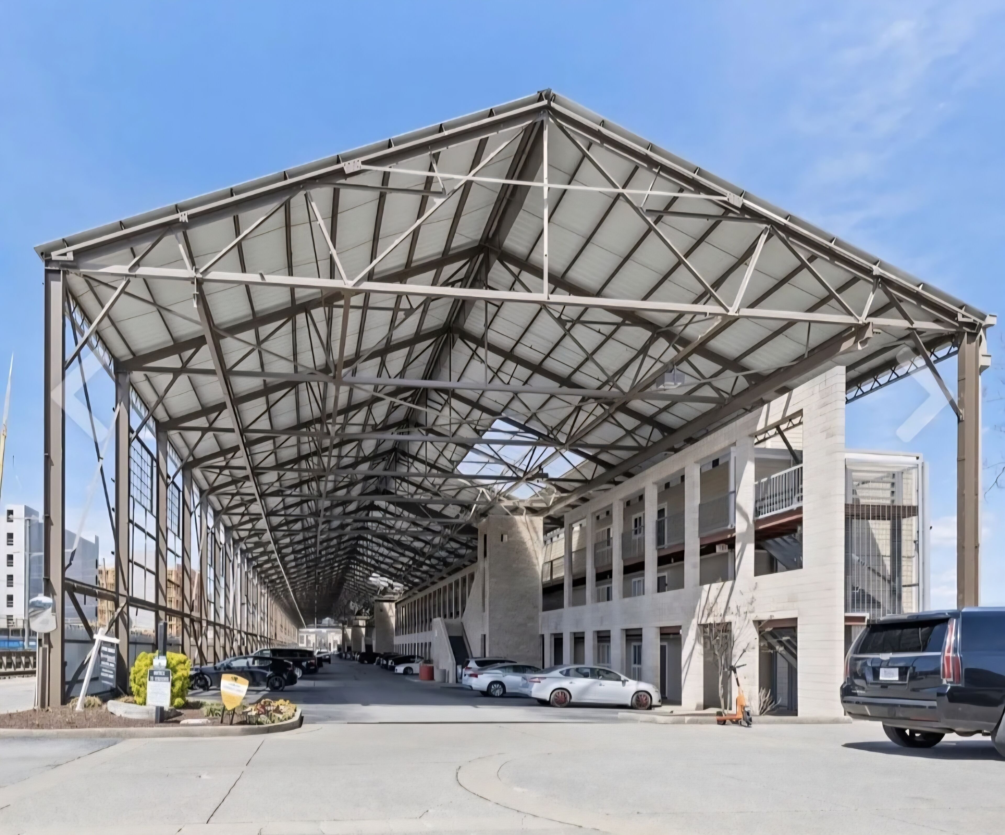Eine mehrstöckige Parkgarage mit Säulen, unter blauem Himmel, mit mehreren parkenden Autos.