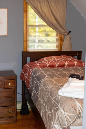 A bedroom with a bed, a nightstand, a window with curtains, and a picture on the wall. - Scenic views in Serene Adirondack retreat (Johnsburg)