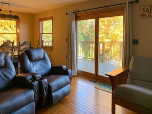A living room with leather sofas, a wooden coffee table, and a sliding glass door leading to an outdoor deck.