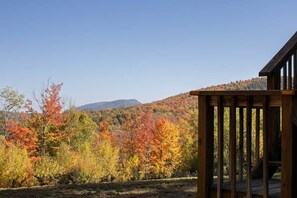 A wooden deck with a view of autumn foliage and distant mountains.