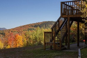 A wooden observation tower with a staircase, surrounded by autumn foliage and a clear sky.
