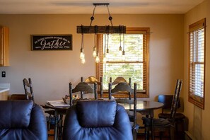 A dining area with a round table, wooden chairs, and a hanging light fixture.