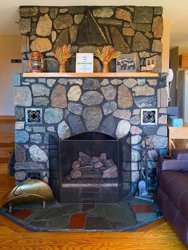 A stone fireplace with a fire, decorative items, and a sign above it.