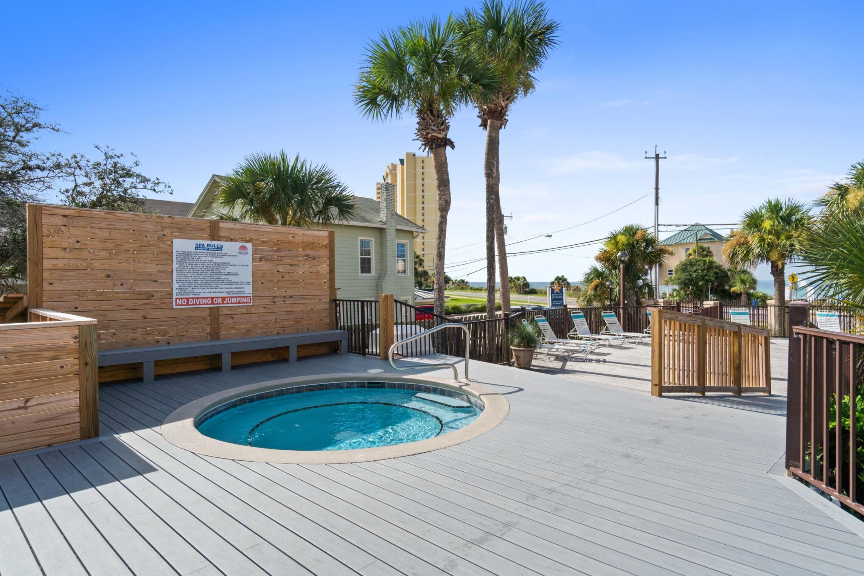 A pool area with a wooden deck, lounge chairs, and a sign indicating no diving or jumping.