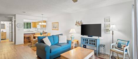 A modern living room with a blue sofa, wooden coffee table, and a flat-screen TV.