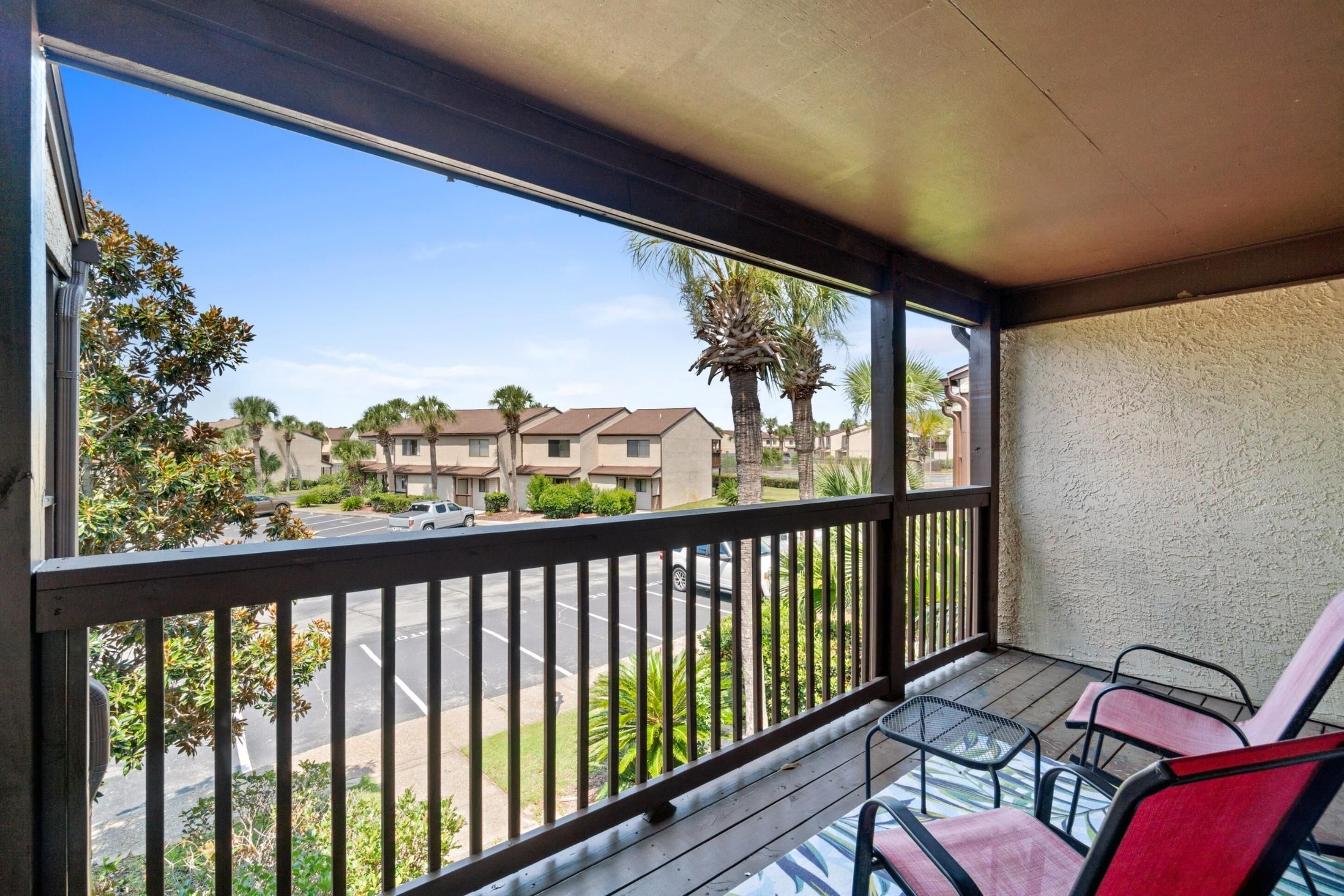 A balcony with a view of a parking lot and residential buildings.