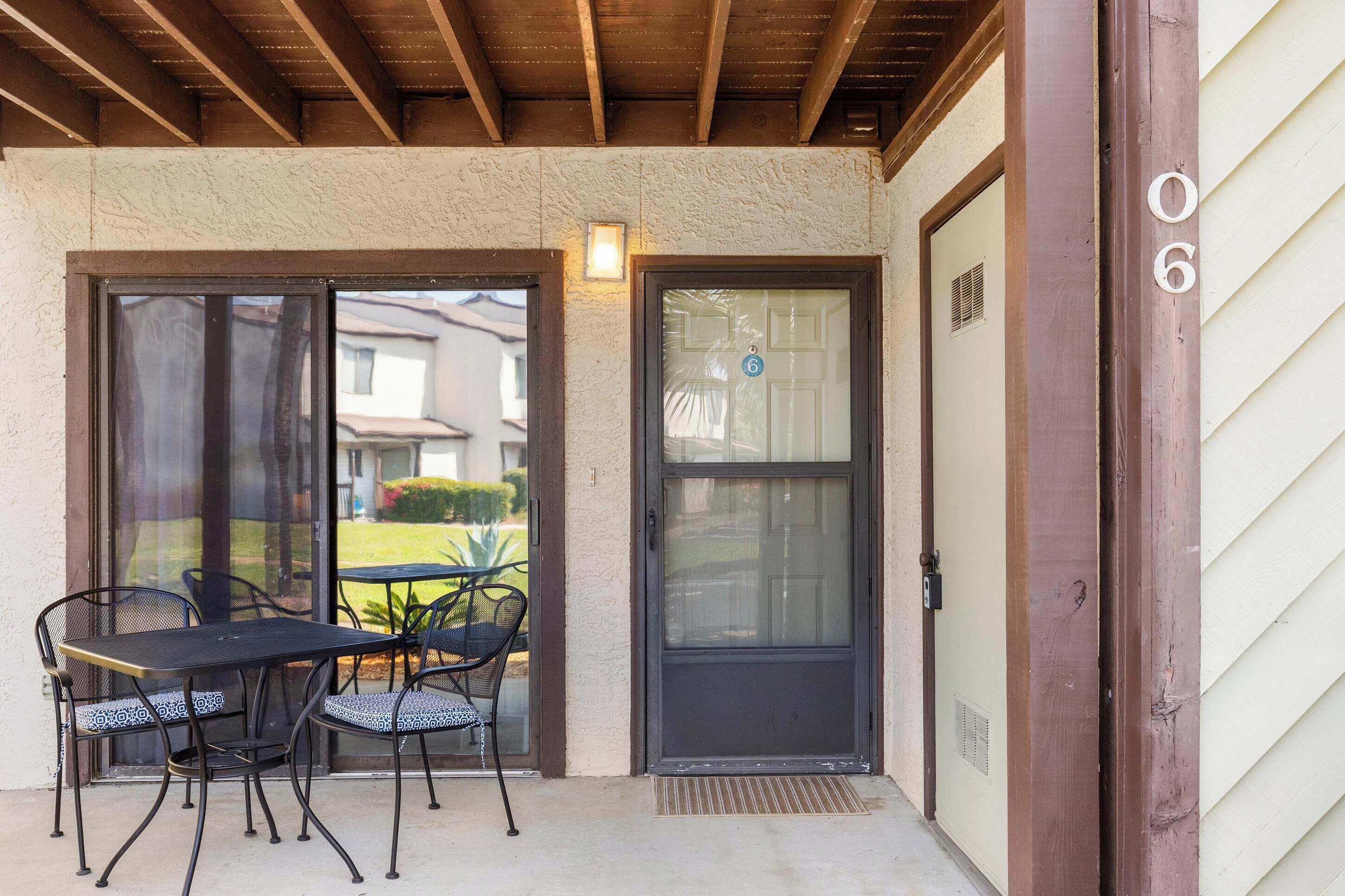 A covered patio with a table and chairs, a sliding glass door, and a number '6' on the wall.