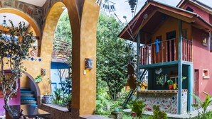 A traditional house with a balcony, stone arches, and a garden with potted plants. - Casa Miguel Arcangel (Coatepec)