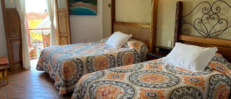 A room with two beds, a painting, a wall-mounted light, and a balcony with a view.