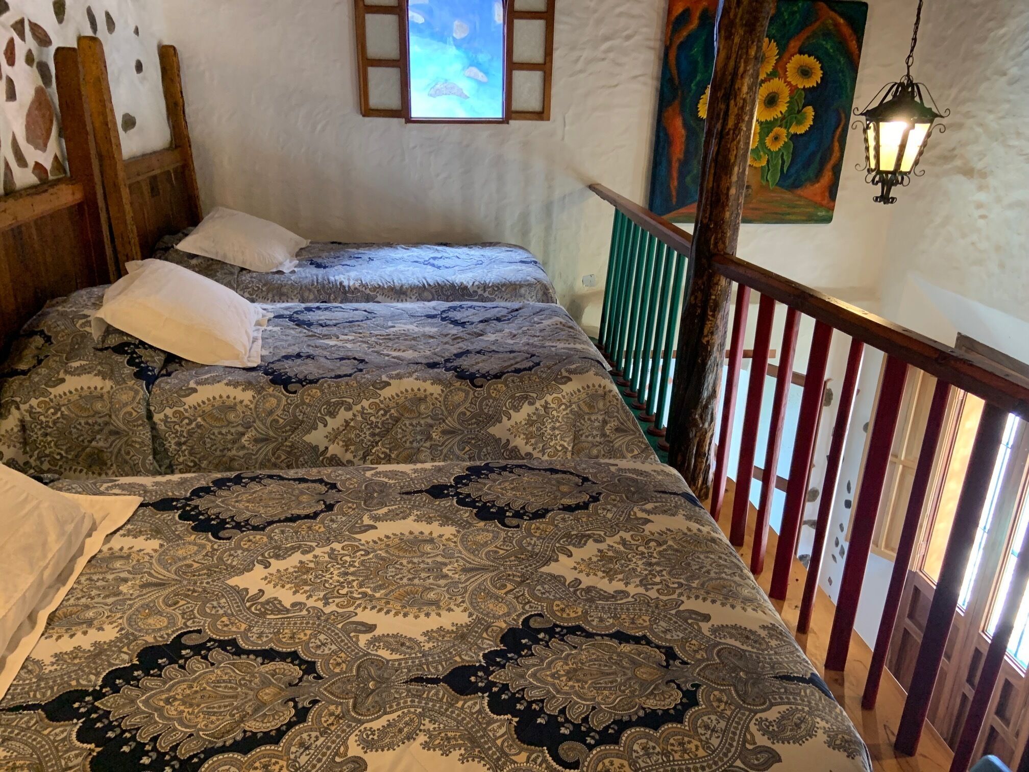 Un dormitorio con dos camas, cabecero de madera, un cuadro y una lámpara colgante.