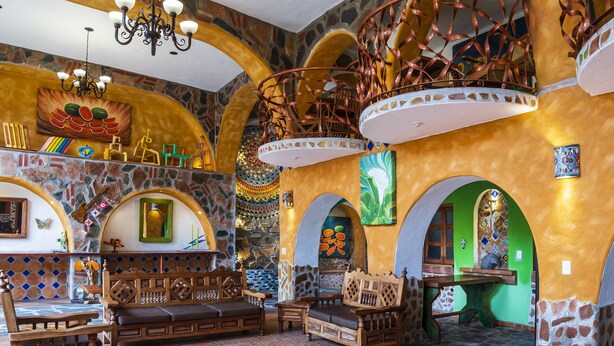 A spacious interior with a high ceiling, stone walls, and a central staircase. - Casa Miguel Arcangel (Coatepec)