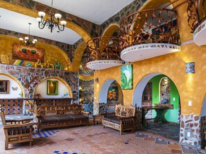 A spacious interior with a high ceiling, stone walls, and a central staircase. - Casa Miguel Arcangel (Coatepec)