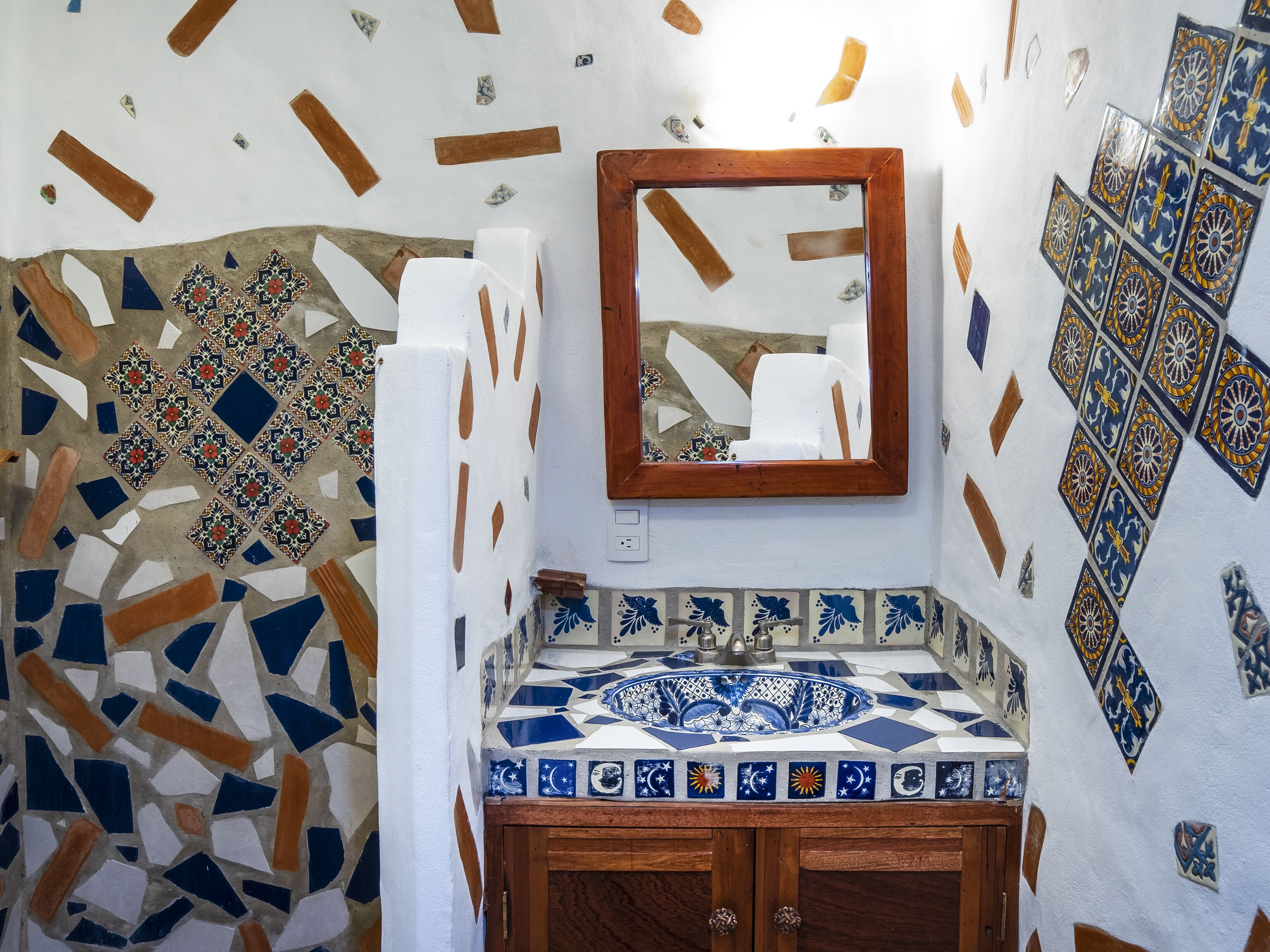 A bathroom with a mosaic tile wall, a wooden vanity, and a mirror.