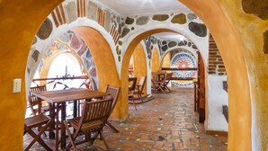 A dining area with a mosaic floor, stone arches, and wooden furniture. - Casa Miguel Arcangel (Coatepec)