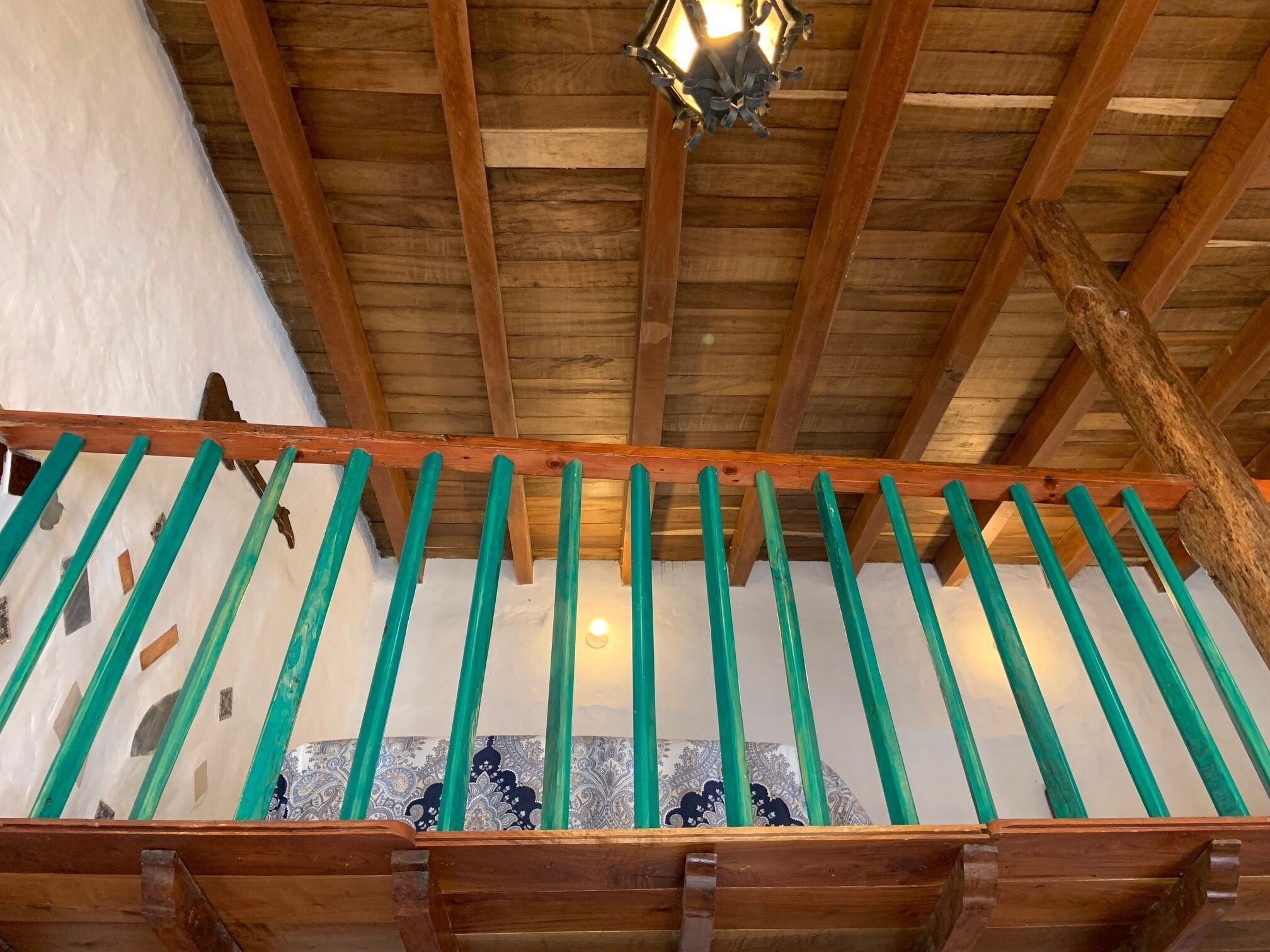 A wooden staircase with green balusters and a patterned wall beneath.