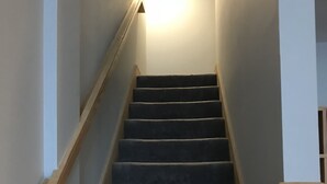 A staircase with carpeted steps and wooden handrails, leading to a landing with a light fixture. - My Snow Slopeside Ski On/Off 4 BR Condo (Dover)