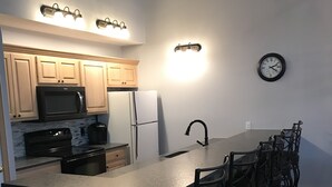 A kitchen with wooden cabinets, a microwave, a refrigerator, a sink, and a clock on the wall. - My Snow Slopeside Ski On/Off 4 BR Condo (Dover)