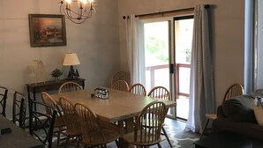 A dining area with a wooden table and chairs, a chandelier, and a painting on the wall. - My Snow Slopeside Ski On/Off 4 BR Condo (Dover)