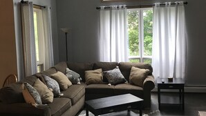 A living room with a large window, a dark brown sectional sofa, a coffee table, and a patterned rug. - My Snow Slopeside Ski On/Off 4 BR Condo (Dover)