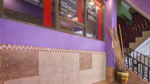 Uma escadaria com corrimão, parede revestida de azulejos e um vaso decorativo com gravetos.