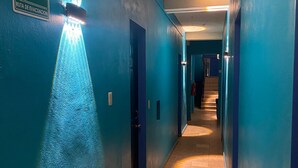 Um corredor com paredes azuis, uma placa de sinalização e um projetor no teto.