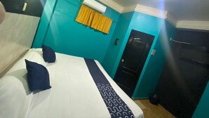 Quarto de hotel com cama, janela com cortinas, porta e unidade de ar condicionado.
