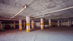 Garagem subterrânea com pilares de concreto e veículos estacionados.
