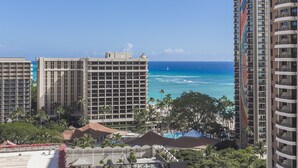 A high-rise hotel with a view of the ocean, featuring multiple balconies and a pool area.