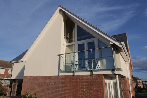 A modern two-story house with a balcony, large windows, and a brick facade.