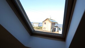 Una ventana de tragaluz con vistas a un edificio de techos inclinados y paneles solares.