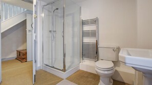 Een badkamer met een glazen douchecabine, toilet en wastafel.