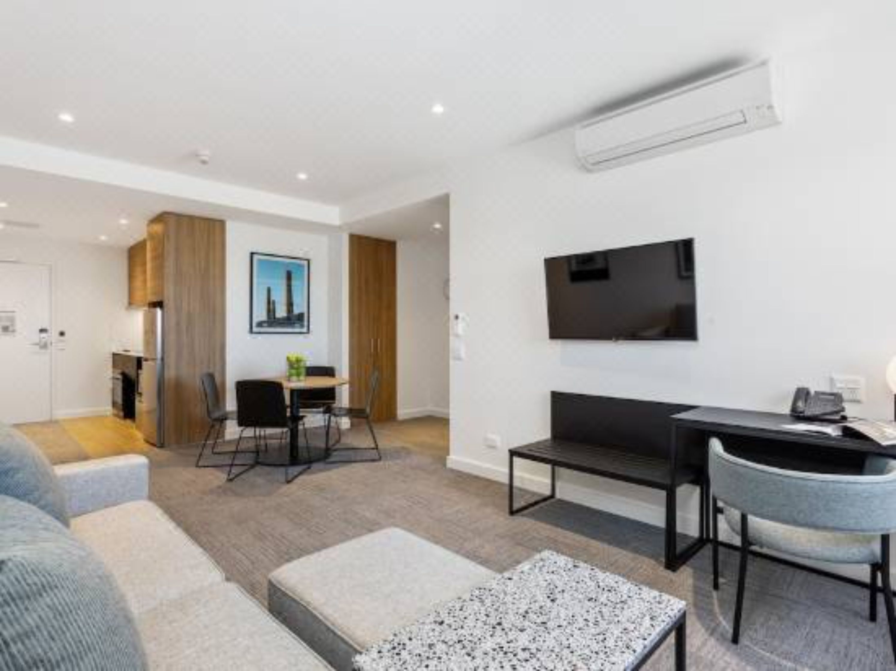 A modern living room with a sofa, a coffee table, and a dining area with chairs and a table.