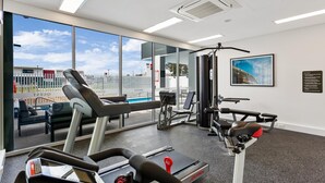 Un gimnasio moderno con equipamiento de cardio, máquinas de pesas y un amplio ventanal con vistas al exterior.
