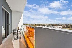 A balcony with a table and chairs, a bottle of champagne, and a clear view of a cityscape.