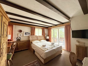 Une chambre à coucher avec un lit, un bureau, une chaise, une télévision et une fenêtre.