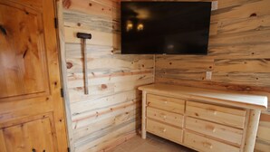 A wooden-paneled room with a flat-screen TV mounted on the wall, a wooden cabinet, and a hammer leaning against the wall. - Farriers Quarters Studio on 280 acre Sevier River Ranch - 2 Queen Beds (Hatch)
