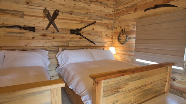 A cabin with two wooden beds, a wooden ceiling, and a rustic interior. - Farriers Quarters Studio on 280 acre Sevier River Ranch - 2 Queen Beds (Hatch)