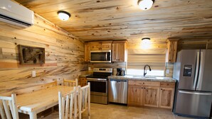 A kitchen with wooden cabinets, a stainless steel refrigerator, a dishwasher, and a wooden dining table with chairs. - Farriers Quarters Studio on 280 acre Sevier River Ranch - 2 Queen Beds (Hatch)