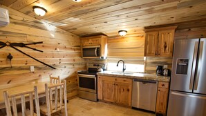 A modern kitchen with wooden walls, stainless steel appliances, and a tiled floor. - Tack Room Studio on 280 acre Sevier River Ranch - 1 King and 2 Twin Beds (Hatch)