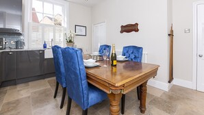 A dining area with a wooden table, blue upholstered chairs, a bottle of champagne, and a map on the wall. - George street Boutique Apartment 1 - sleeps 6 guests  in 2 bedrooms (York)