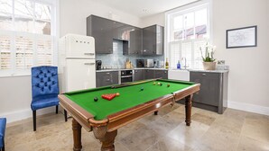 A pool table in a modern kitchen with grey cabinets, a blue chair, and a potted plant on the counter. - George street Boutique Apartment 1 - sleeps 6 guests  in 2 bedrooms (York)