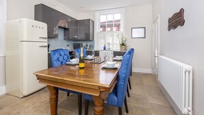 A modern kitchen with a dining table, blue upholstered chairs, a white refrigerator, and a white radiator. - George street Boutique Apartment 1 - sleeps 6 guests  in 2 bedrooms (York)