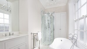 Ein modernes Badezimmer mit einer freistehenden Badewanne, einer Duschkabine und einem Waschtisch mit großem Spiegel.