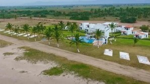 A large, modern resort with multiple buildings, a swimming pool, and palm trees. - Color Marino Seaside Hotel (Escuinapa)
