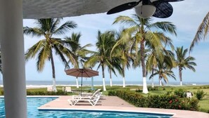 A pool area with lounge chairs, a table, and a ceiling fan. - Color Marino Seaside Hotel (Escuinapa)