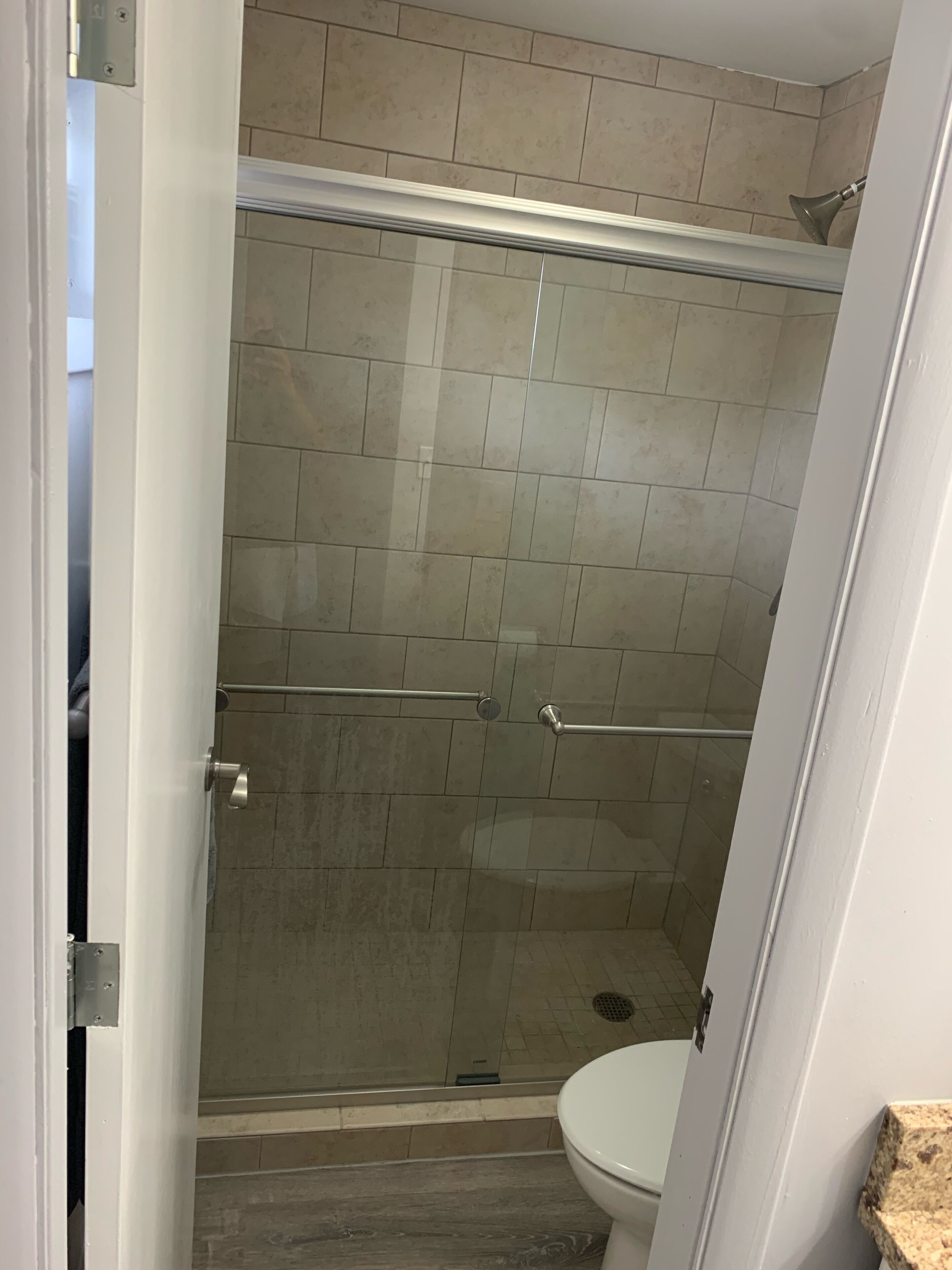 A bathroom with a glass-enclosed shower, a toilet, and a sink.