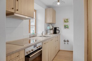 Ett modernt kök med träskåp, en inbyggd ugn, en diskho och en kaffebryggare.
