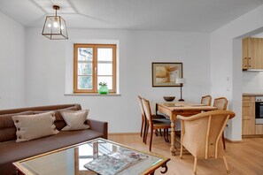 Ett modernt vardagsrum med en soffa, ett matbord, stolar och en köksdel.