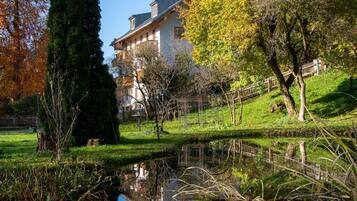 Ein friedlicher Park mit Teich, Bäumen und einem Gebäude im Hintergrund.